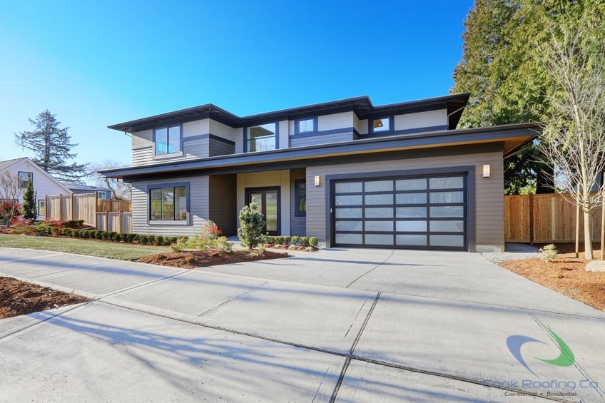 Top Quality Residential Roofing 2 New construction home exterior with contemporary house plan features low slope roof, brown siding and glass garage door.