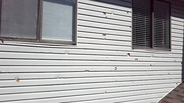 Siding with holes from hail damage also with hail damage on screens and windows