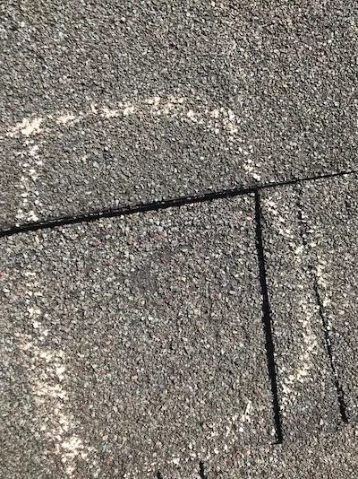 Hail damaged shingle with chalk outline