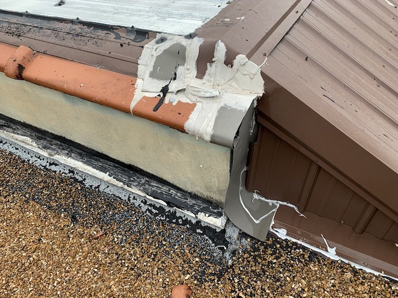 Metal roof flashing at parapet wall with a lot of caulking and gaps