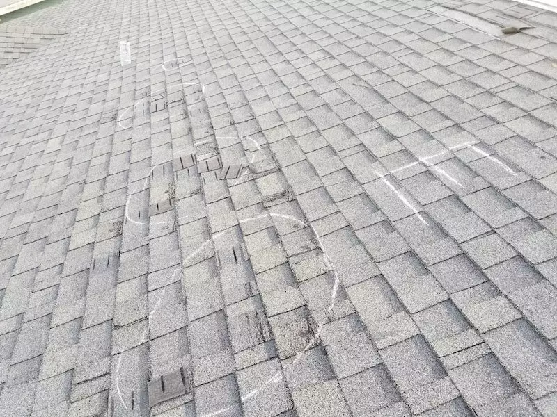 Missing shingle tabs and creased shingles damaged by wind