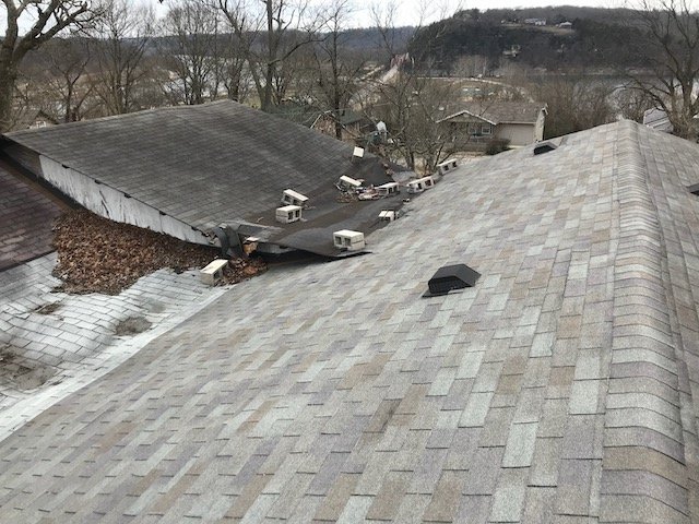 Roof repair gone wrong - this roof has been repaired too many times and needs to be replaced. Roof with concrete blocks holding down rolled roofing, and sunken warped decking