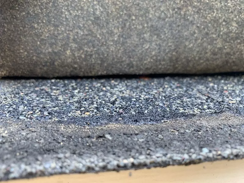 Lifted shingle tab with dirt stuck to mastic